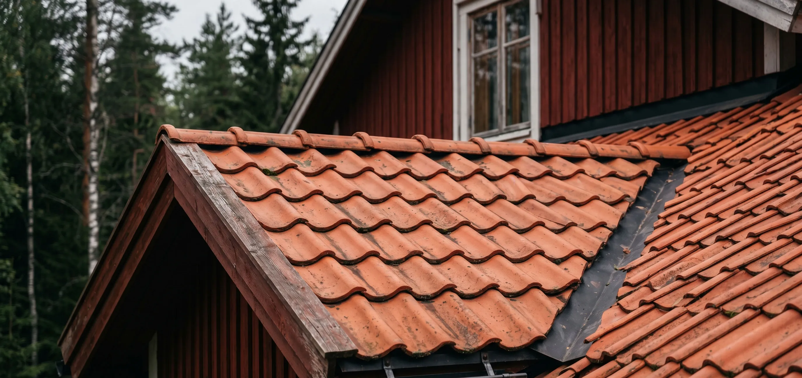 Punaisen puutalon tiilikatto, jossa harja ja jiiri näkyvissä
